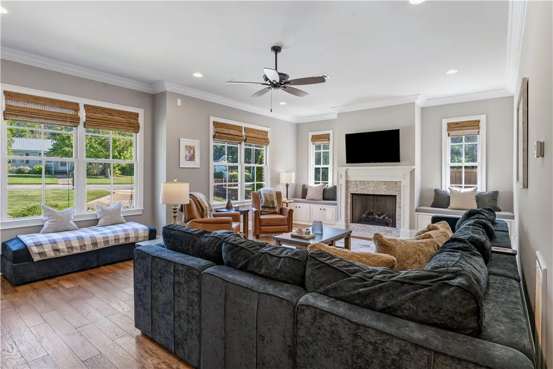 Rich hardwood flooring and crown molding frame a central fireplace bordered by built-in window seating.