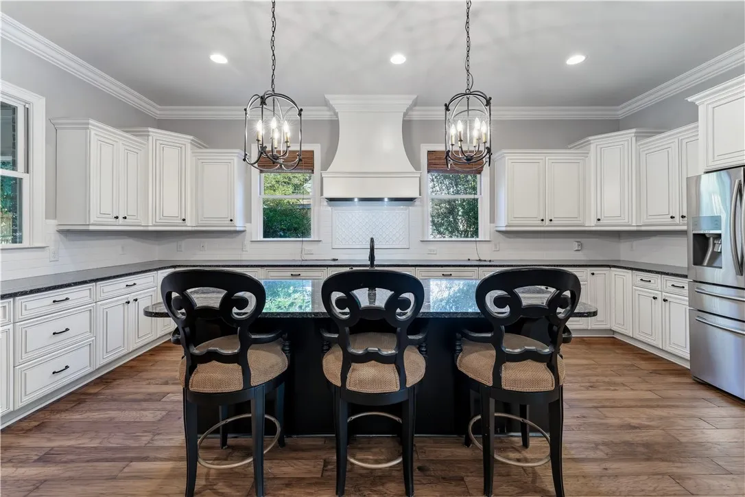 Crisp white cabinetry, stone countertops, and warm wood-look flooring define this classic culinary space.