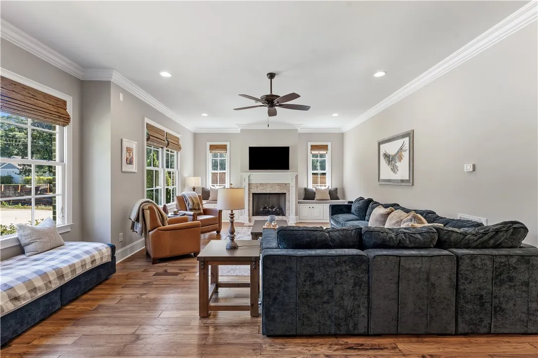 Rich hardwood flooring, clean crown molding, and a warm central fireplace anchor this inviting living space.