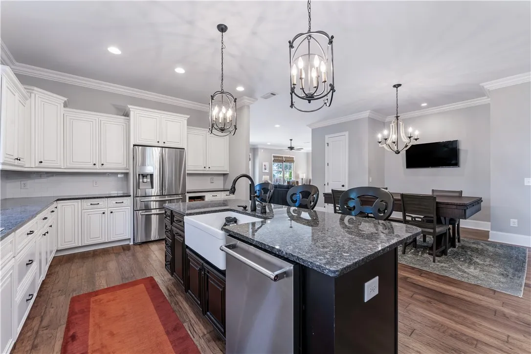 Rich wood flooring pairs perfectly with dark granite countertops in this open culinary layout.