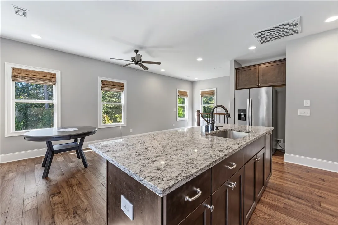 Rich wood flooring anchors this open-concept culinary space detailed with granite counters.