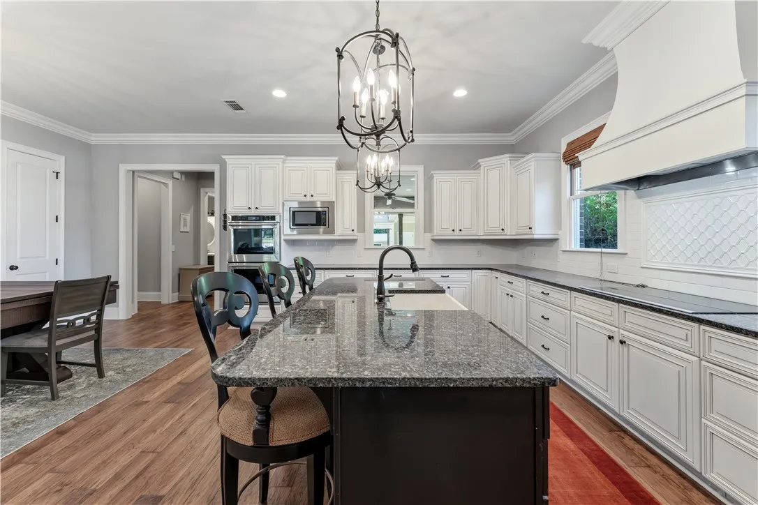 Polished granite countertops and classic white cabinetry define this spacious, light-filled kitchen space.