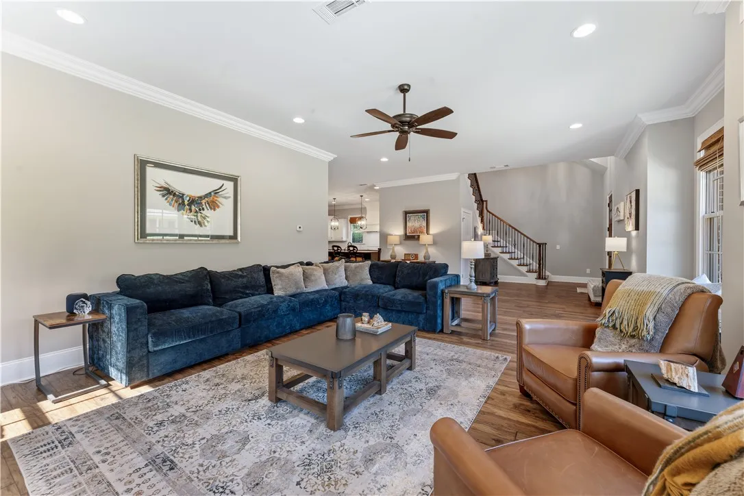 Warm wood flooring, elegant crown molding, and recessed lighting define this inviting open-concept space.