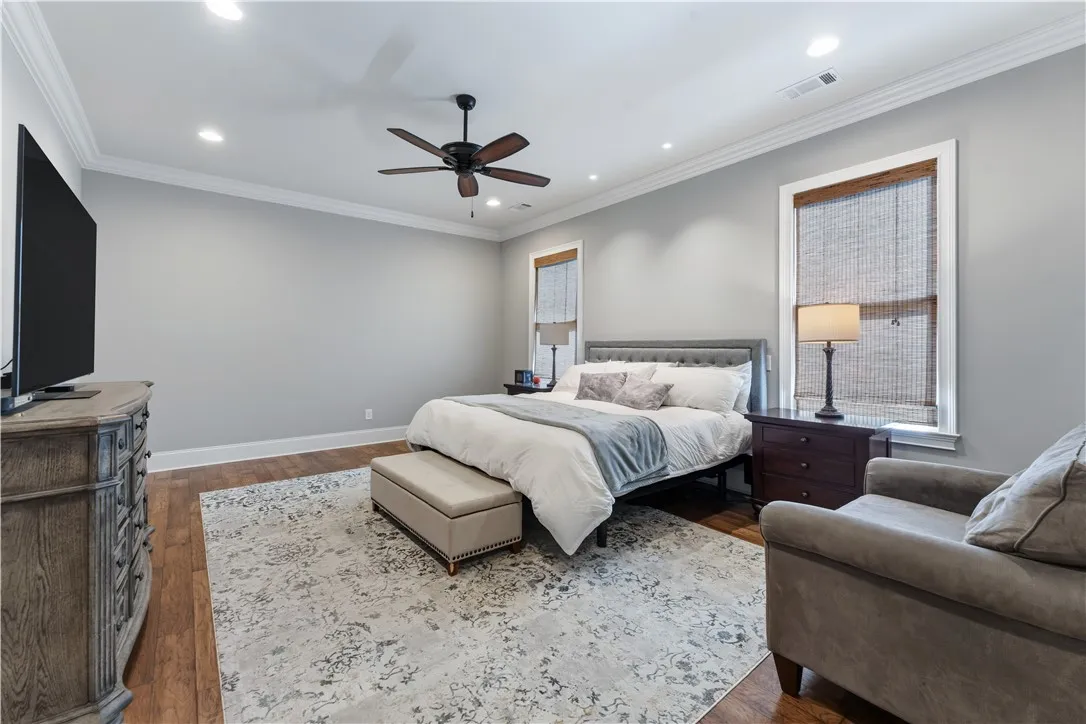 Rich hardwood floors and elegant crown molding elevate this serene bedroom retreat.