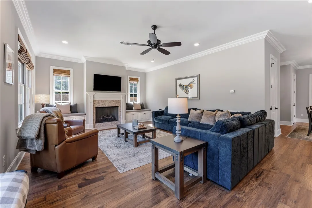 Rich hardwood floors and elegant crown molding frame a welcoming fireplace surrounded by built-in bench seating.