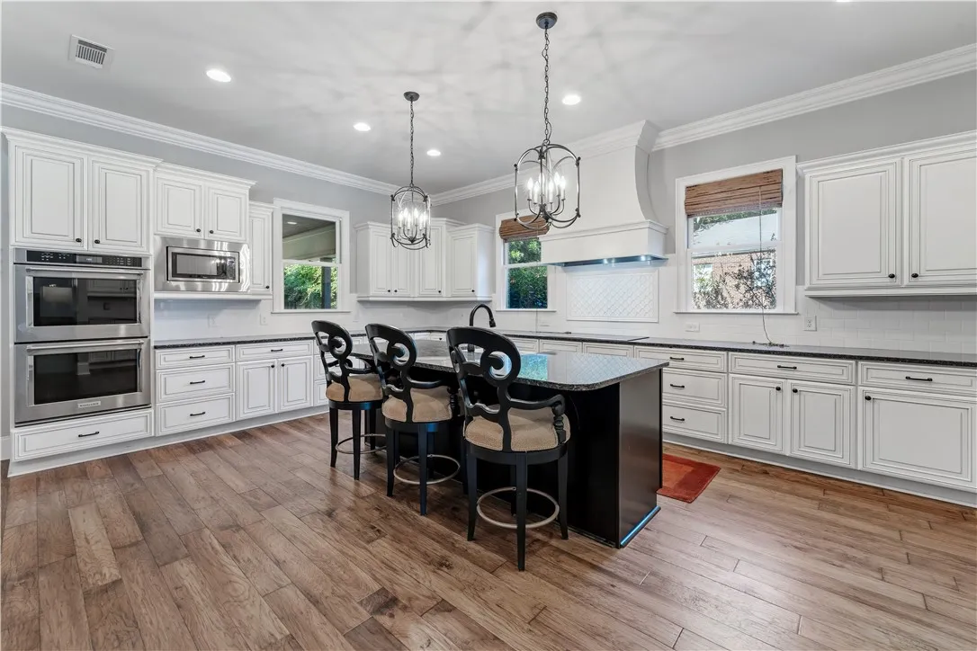 Rich hardwood flooring complements custom white cabinetry and a generous dark kitchen island.