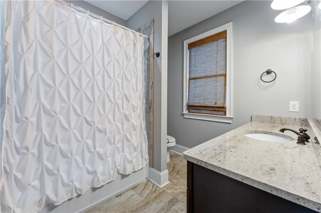 Polished granite counters and elegant tile flooring define this modern, comfortable bathroom space.