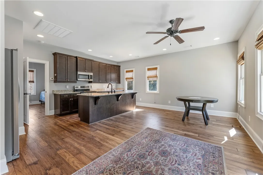 Rich hardwood flooring complements dark cabinetry in this open kitchen and dining area.