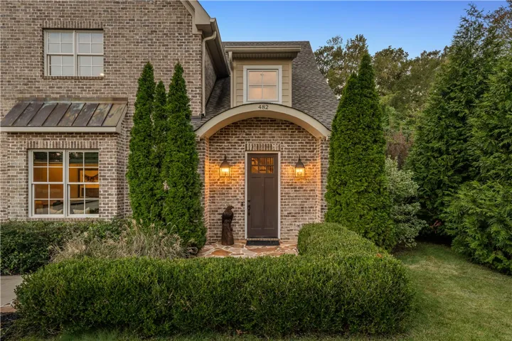 An arched brick entryway creates a welcoming architectural statement framed by manicured landscaping.