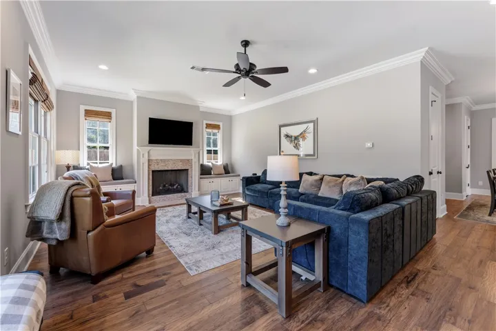 Rich hardwood floors and elegant crown molding frame a welcoming fireplace surrounded by built-in bench seating.