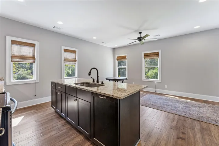 Rich hardwood floors complement the expansive granite-topped kitchen island in this open-concept layout.