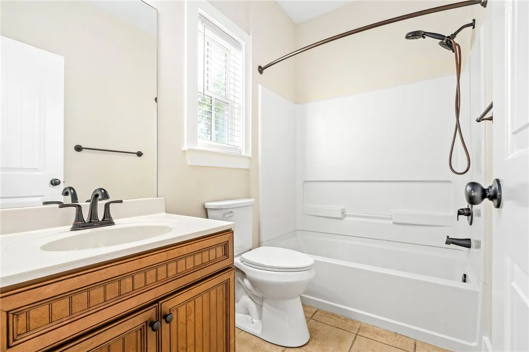 A well-appointed bathroom features a wooden vanity, tile flooring, and a combined tub and shower.