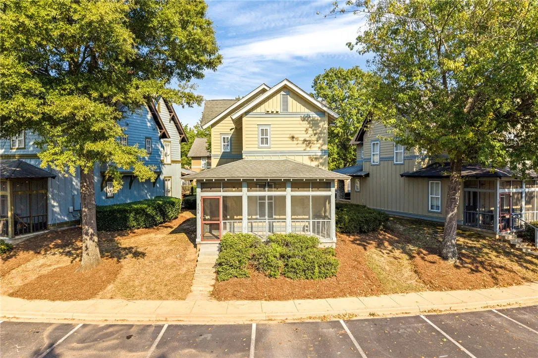 An inviting screened porch highlights this charming multi-story home nestled behind mature shade trees.