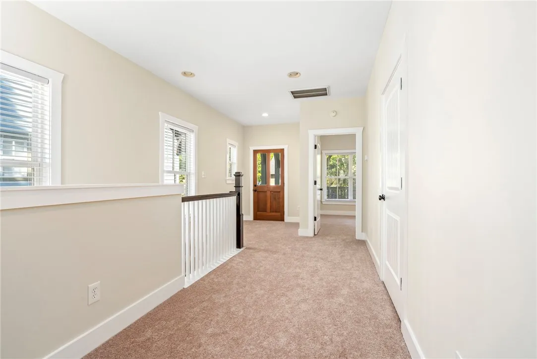 An airy upper landing features plush carpeting, recessed lighting, and a classic wood balustrade.