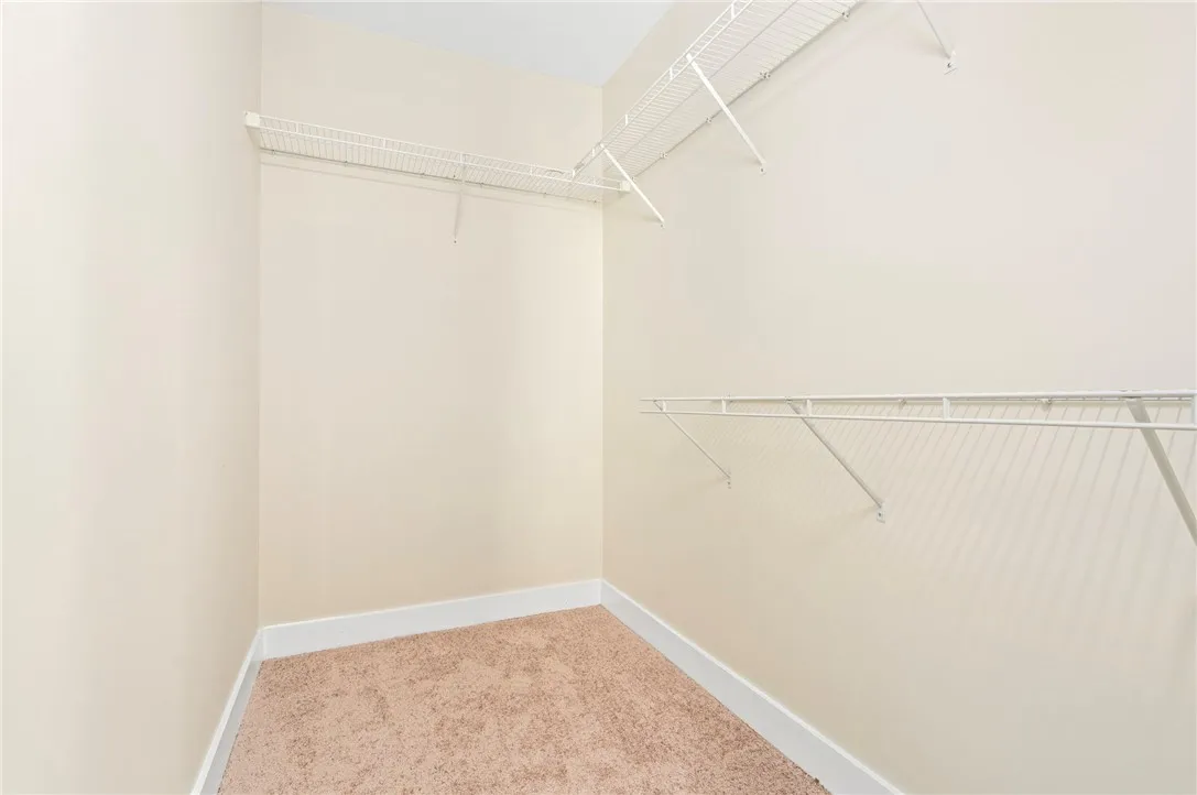 Functional storage space defined by neutral carpet and versatile wire shelving units.