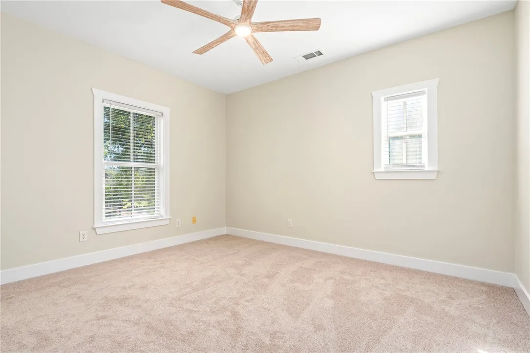 Plush carpeting anchors this versatile room illuminated by dual windows framed in crisp trim.