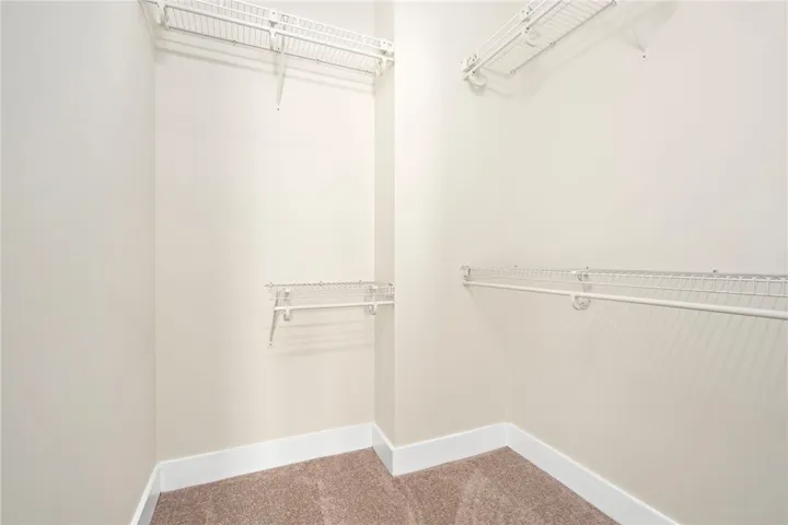 Ample wire shelving and soft carpeting define this functional walk-in closet space.