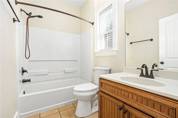 Functional layout incorporates a classic tub shower, solid wood vanity, and tile floors.