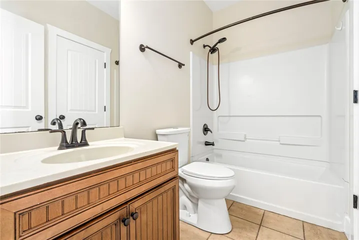 Warm wood cabinetry and neutral tile flooring anchor this functional full bath layout.
