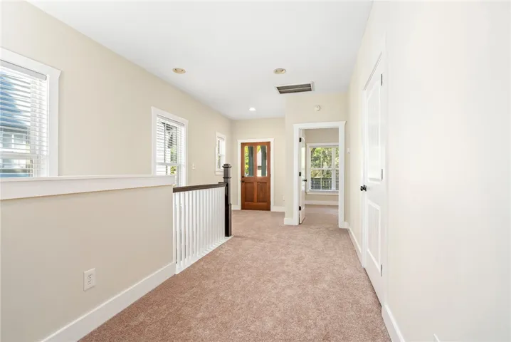 An airy upper landing features plush carpeting, recessed lighting, and a classic wood balustrade.