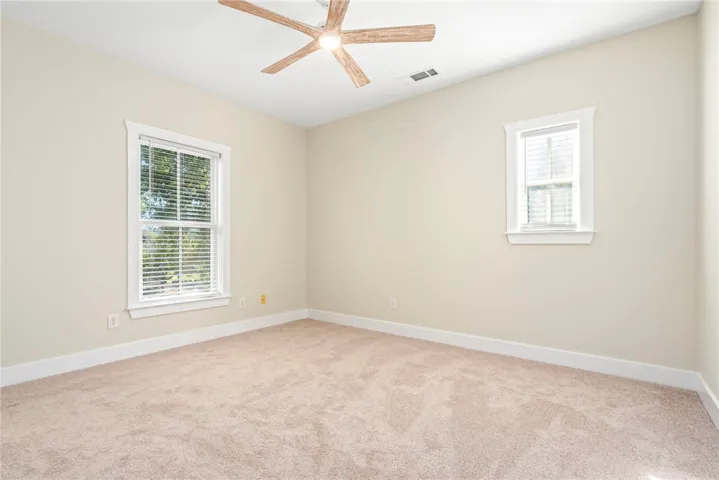 Plush carpeting anchors this versatile room illuminated by dual windows framed in crisp trim.