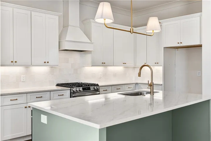 Crisp white cabinetry pairs with a central island and elegant stone countertops.