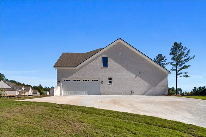 An expansive concrete driveway leads directly to a side-entry garage on this brick exterior.