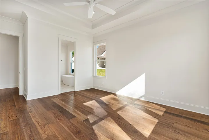 Gleaming hardwood floors and a tiered tray ceiling define this elegant main bedroom suite.