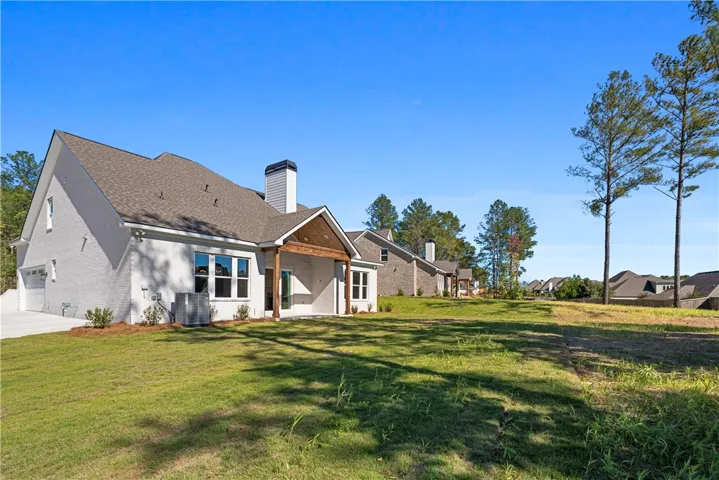 A spacious green lawn borders the handsome brick exterior and covered patio of this home.