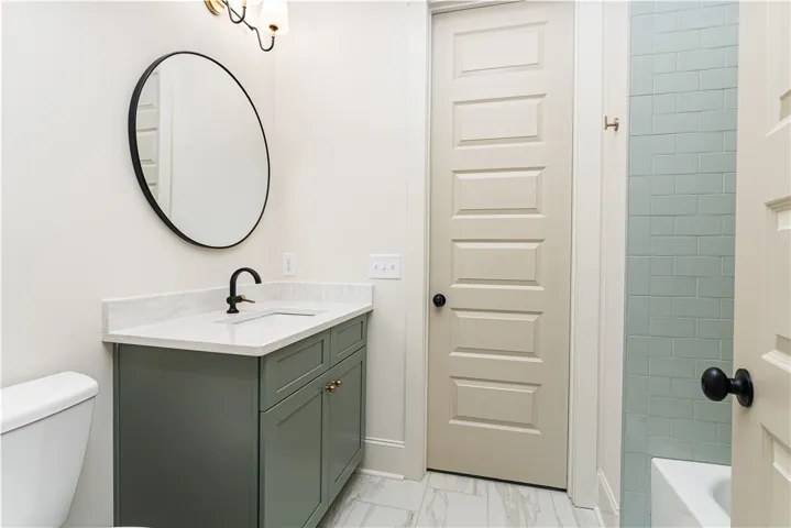 Sleek modern fixtures complement clean vertical tiling and marble-inspired floors in this refined bath.