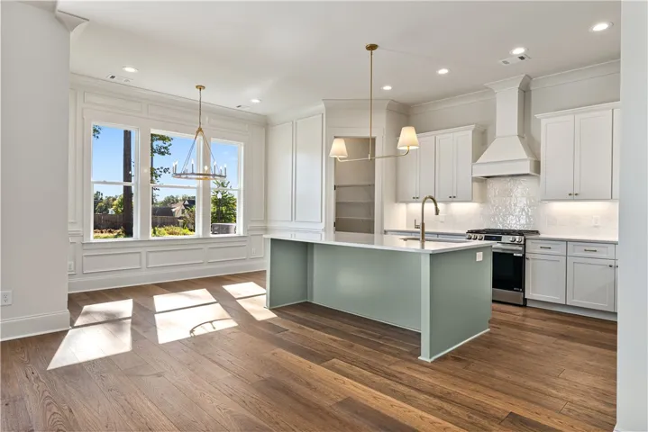 Rich hardwood flooring anchors this airy kitchen featuring a central island and wainscoted breakfast area.