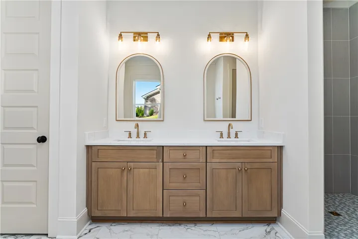 A refined double vanity with stone counters anchors this sleek, modern bathroom space.