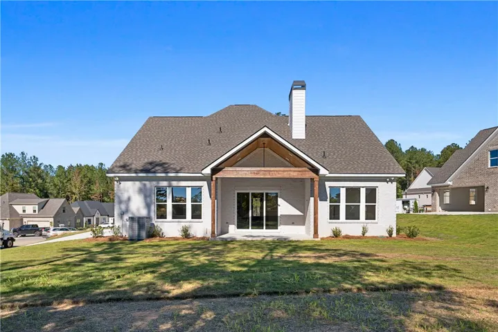 A covered back porch with natural wood beams highlights the rear facade of this home.