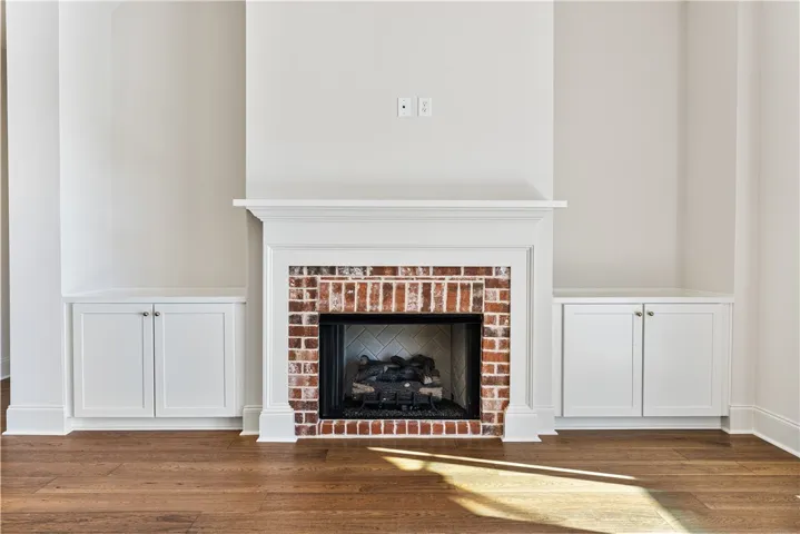 Rich hardwood flooring anchors the living area around a classic brick fireplace flanked by built-ins.