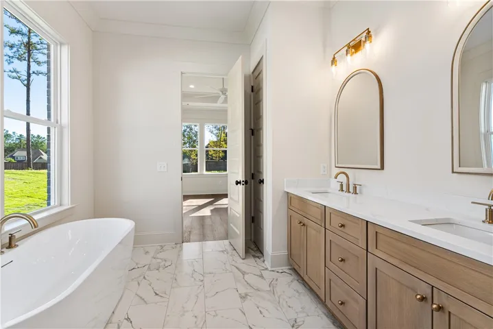 A freestanding tub and double vanity with stone counters define this master bathroom.