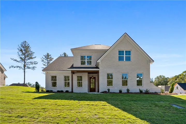 An elegant brick facade rises above a manicured lawn under clear blue skies.