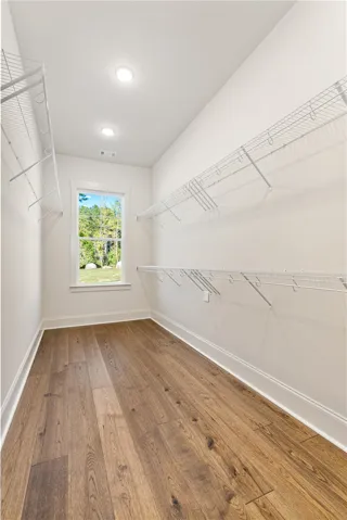 A spacious walk-in closet boasts generous built-in shelving, recess lighting, and a garden view window.