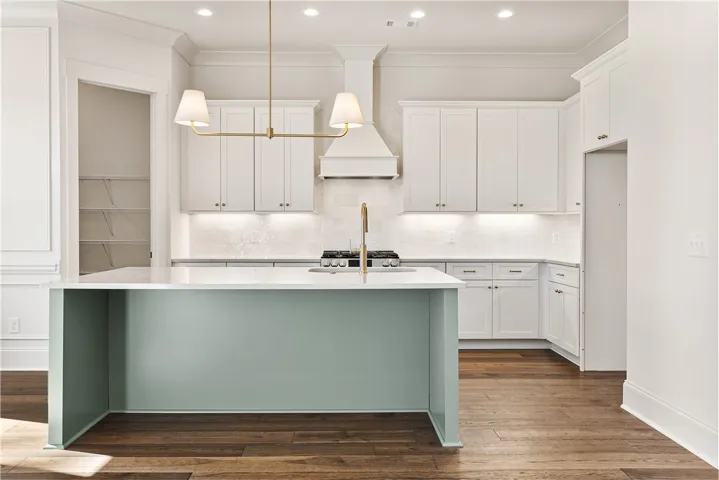 Rich hardwood floors complement clean white cabinetry and a contrasting center island.
