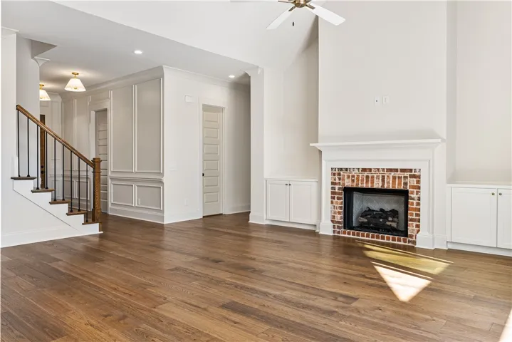 Rich hardwood flooring complements a classic brick fireplace flanked by custom built-ins.