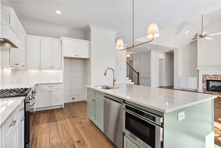 Rich hardwood flooring anchors this airy kitchen featuring custom cabinetry and a spacious central island.