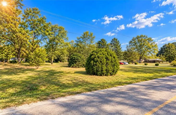 Mature trees and neat greenery frame this inviting, level parcel under a clear sky.