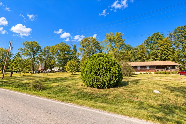 A spacious green lawn surrounds a classic wood-sided home set back from the road.