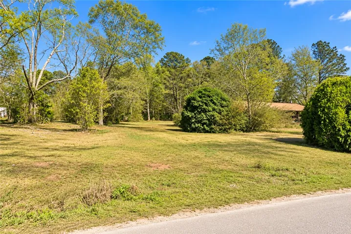 A spacious grassy lawn bordered by mature trees creates a private natural retreat.