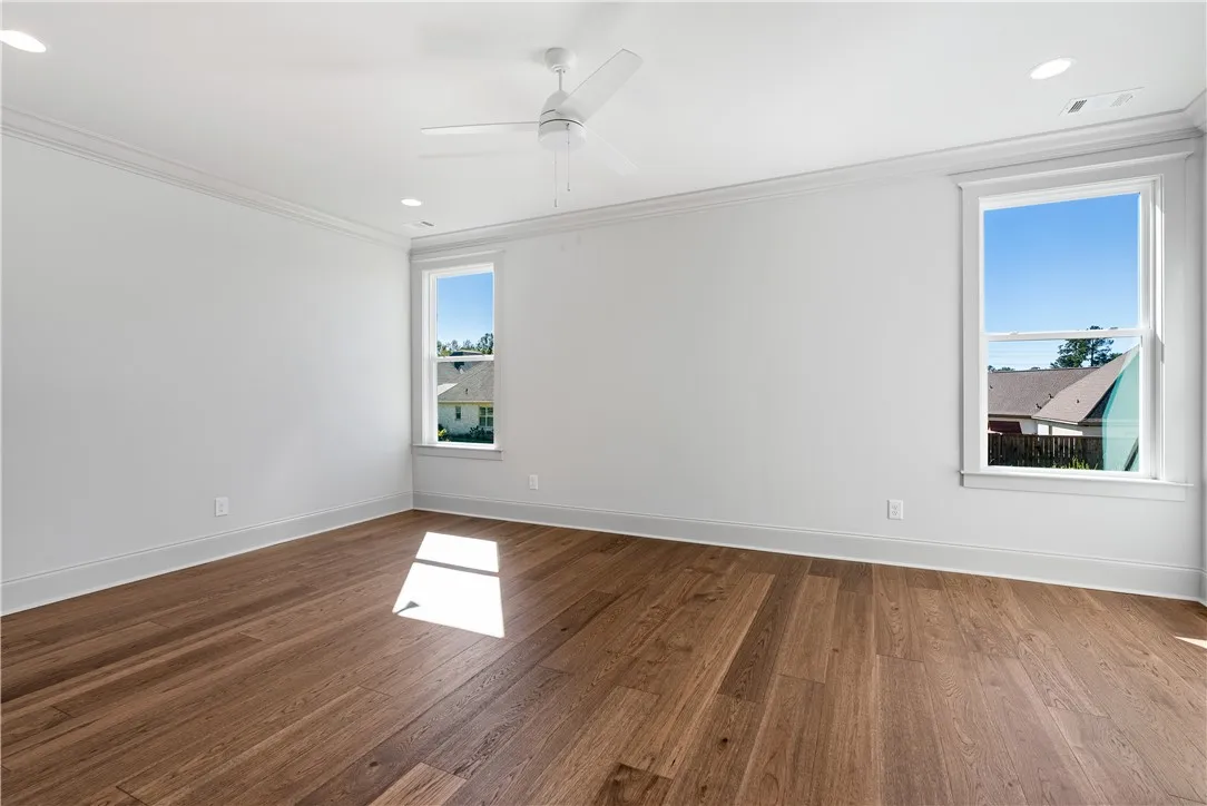 Rich hardwood flooring complements the crisp white walls and crown molding in this versatile space.