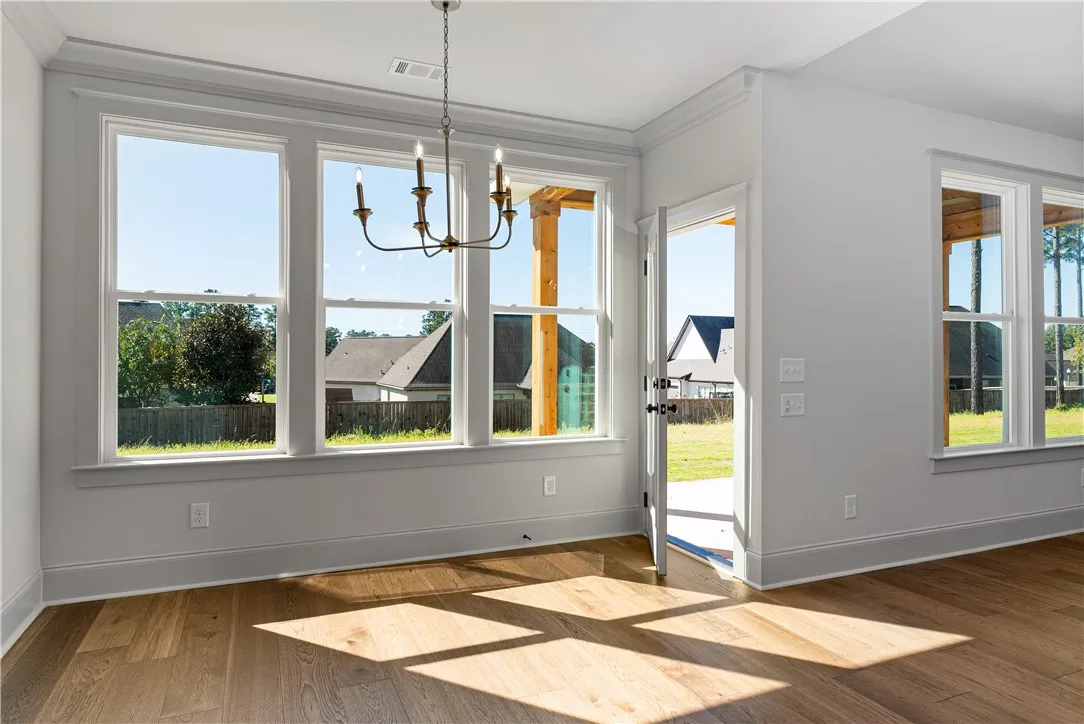 Warm sunlight streams across rich hardwood floors in this open dining area.