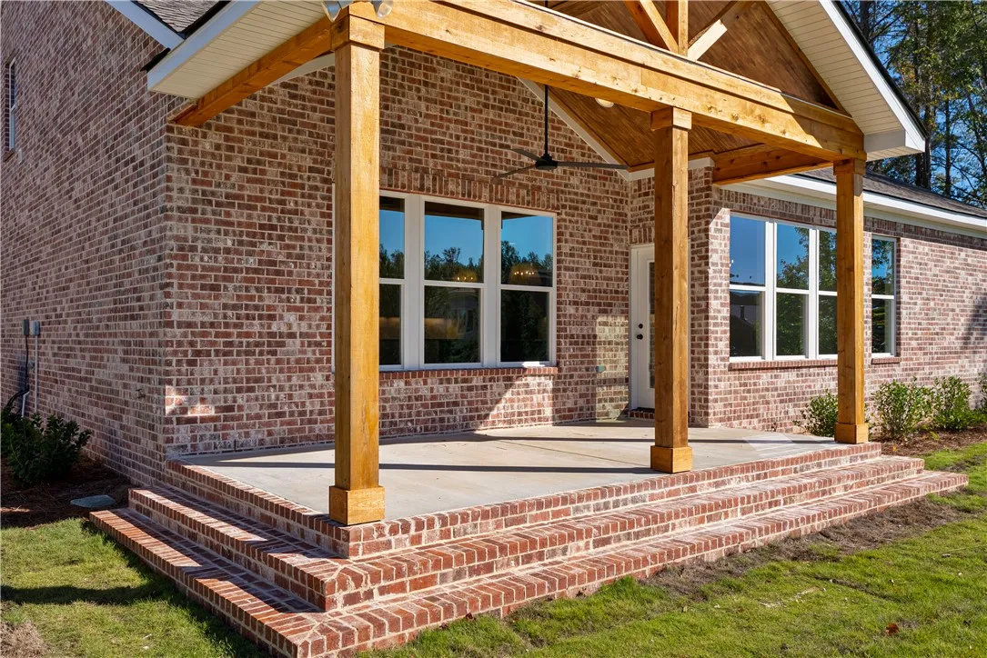 Rich brickwork and heavy timber columns frame a welcoming covered back porch with vaulted wood ceilings.