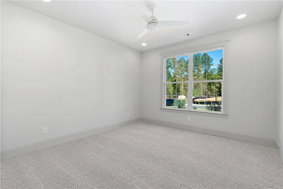 Plush carpeting and a large window framing wooded views define this versatile space.