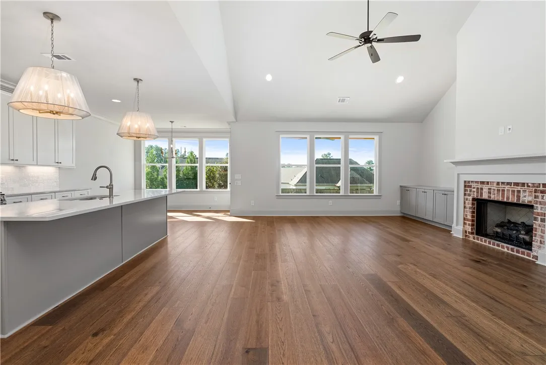 Rich hardwood flooring anchors this airy open floorplan, showcasing a classic brick fireplace.