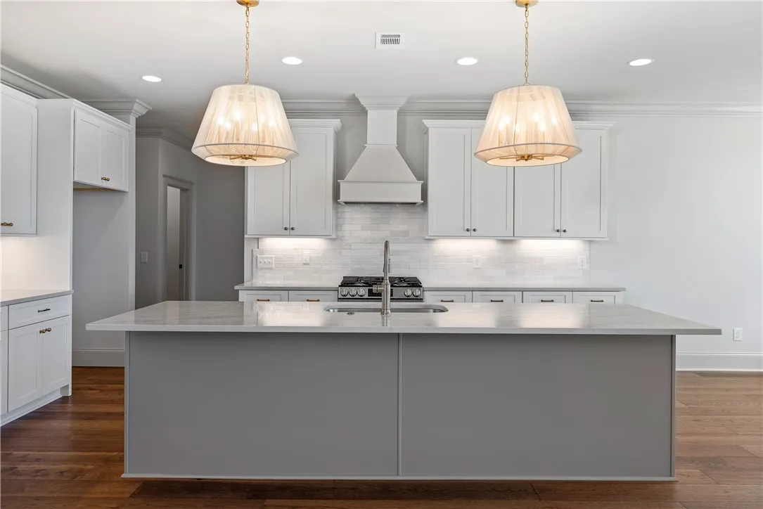 An expansive kitchen island anchors the space, framed by timeless cabinetry and elegant lighting.