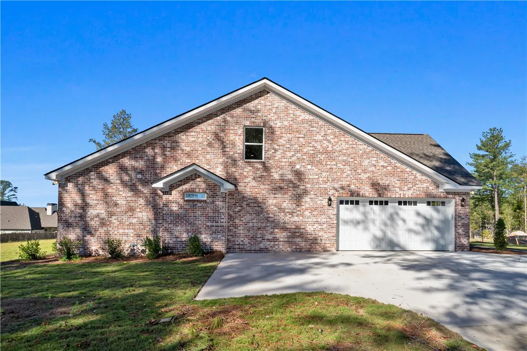 Brick exterior showcases a multi-car garage paired with a concrete driveway and grassy yard.